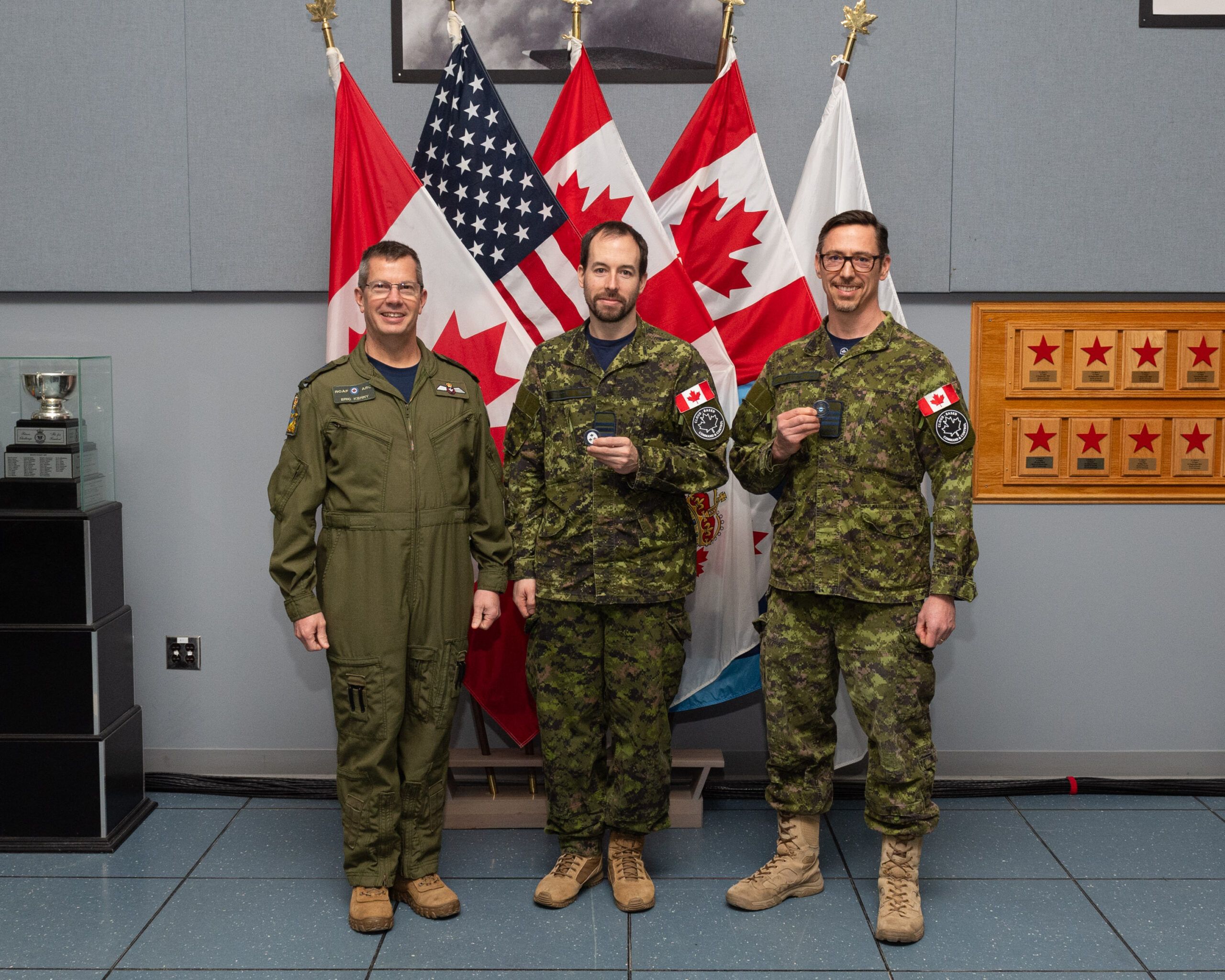 Two members holding coins with the RCAF Comd